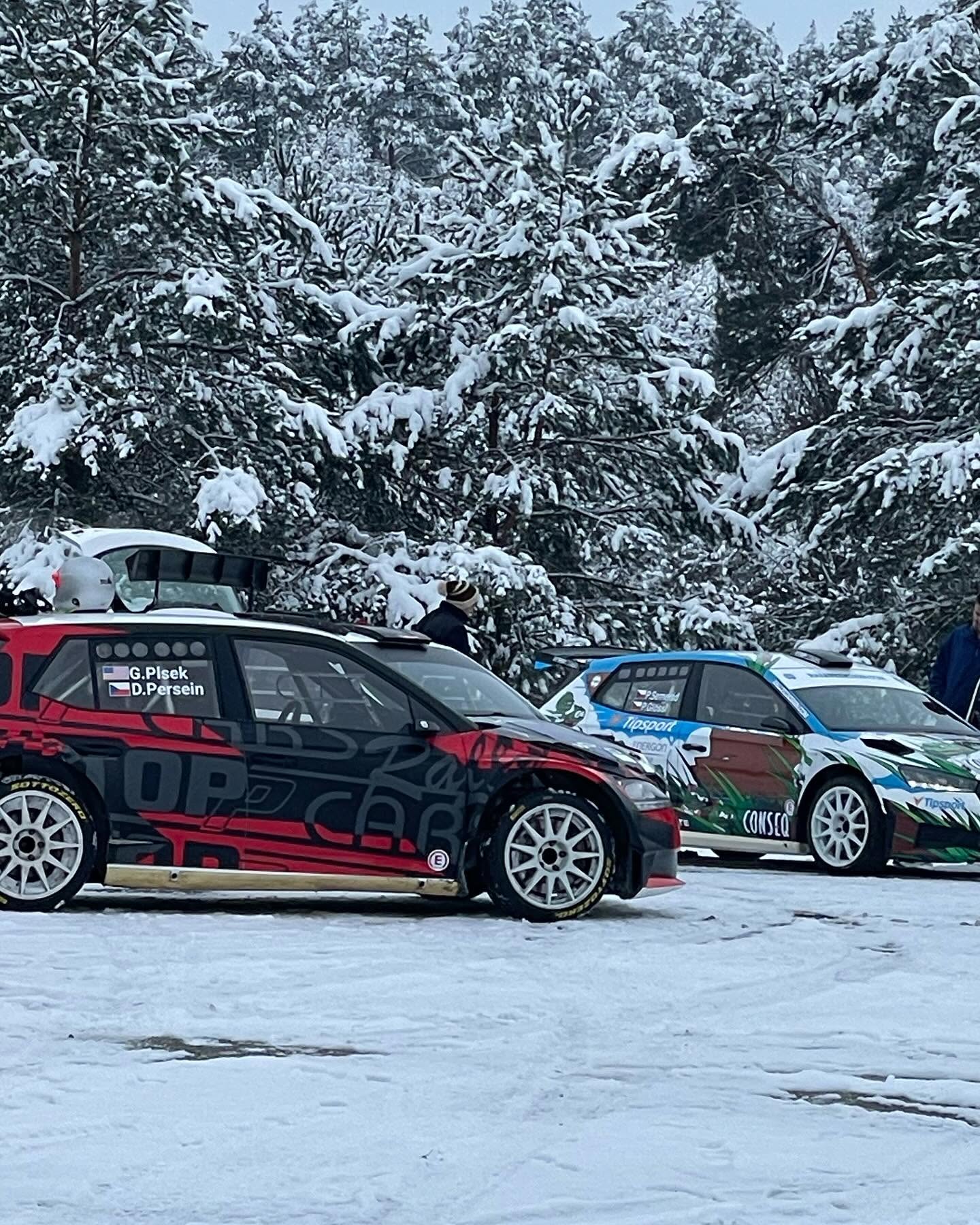 Cars in a snowy service area surrounded by pine trees